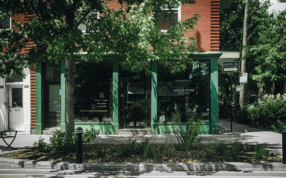 A white retail storefront with a large display window showing a minimalist interior with hanging clothing and a sign that reads 'New Arrivals Collection' for the Sunspe boutique. The shop name 'SUNSPE